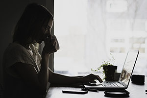 Woman drinking coffee at laptop